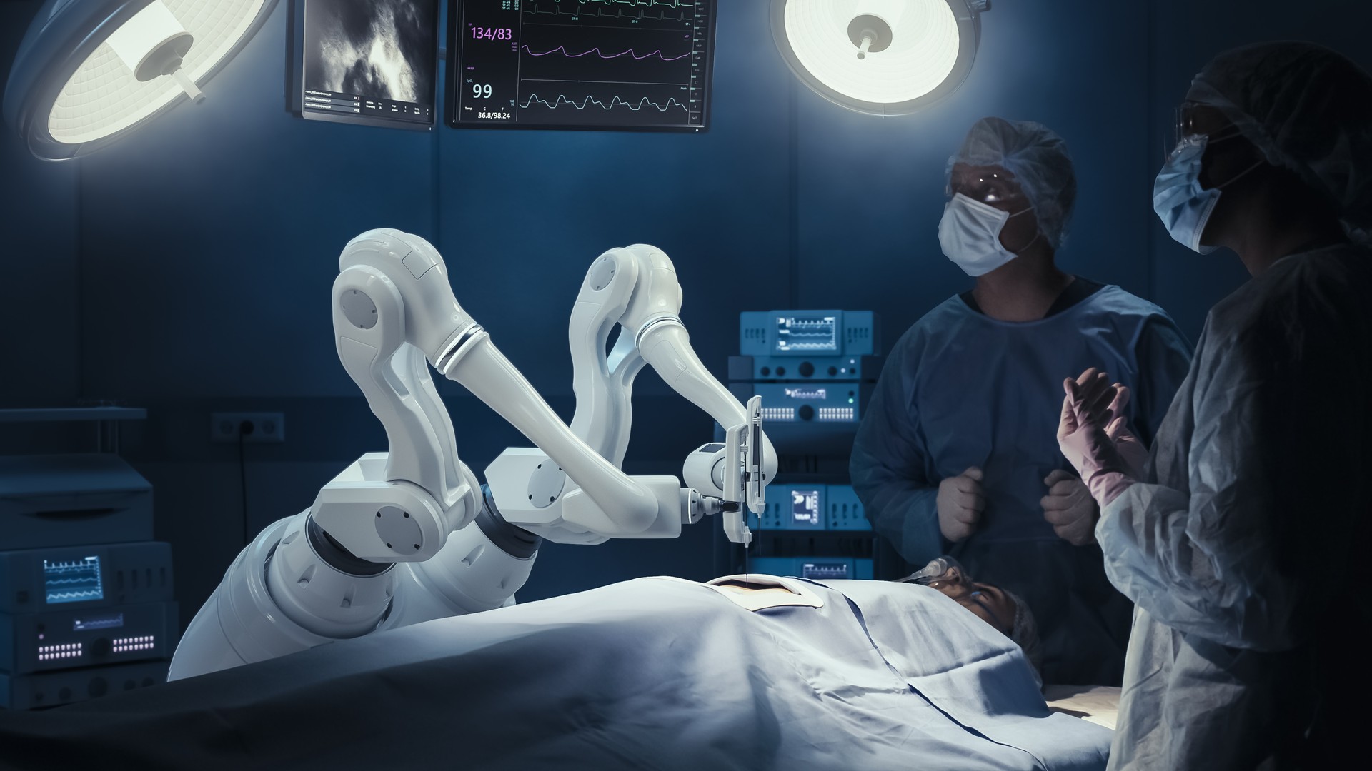 Two Surgeons Observing High-Precision Programmable Automated Robot Arms Operating Patient In High-Tech Hospital. Robotic Limbs Performing Complicated Nanosurgery, Doctors Looking At Vitals On Monitor.